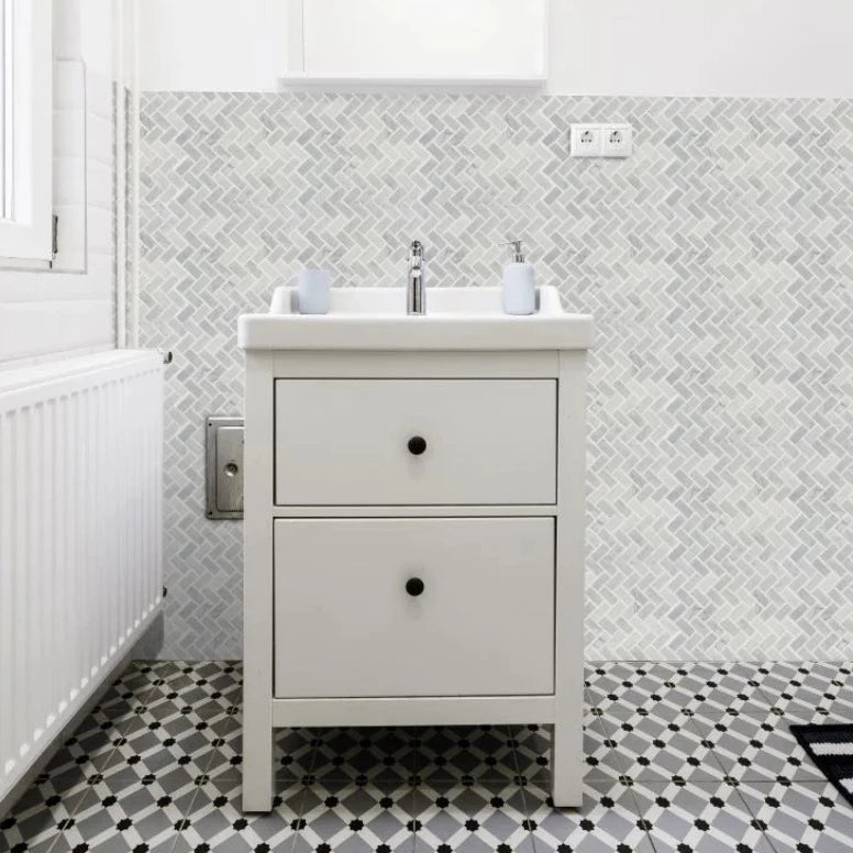cloud sliced pebble tile flooring in a small bathroom with white walls and a tan sink cabinet