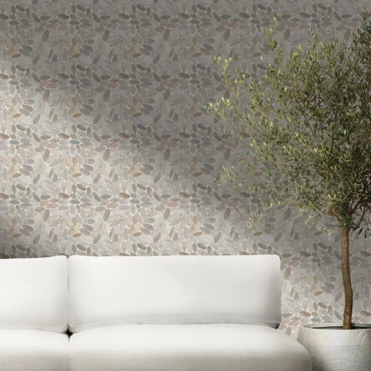 pebble tile wall with white couch in front along with a decorative tree